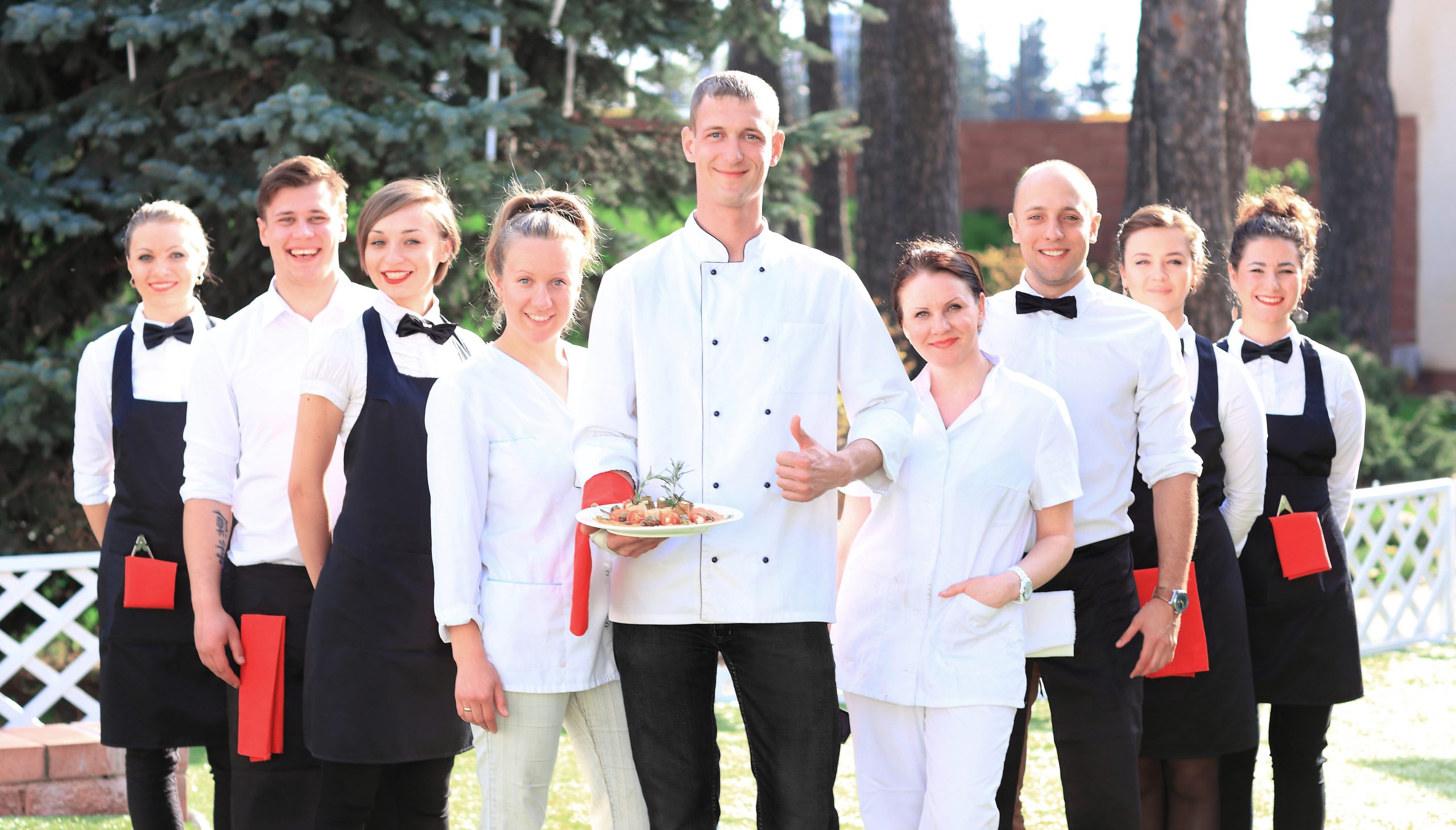 large group of cooks and waitresses stand in a row behind the chef